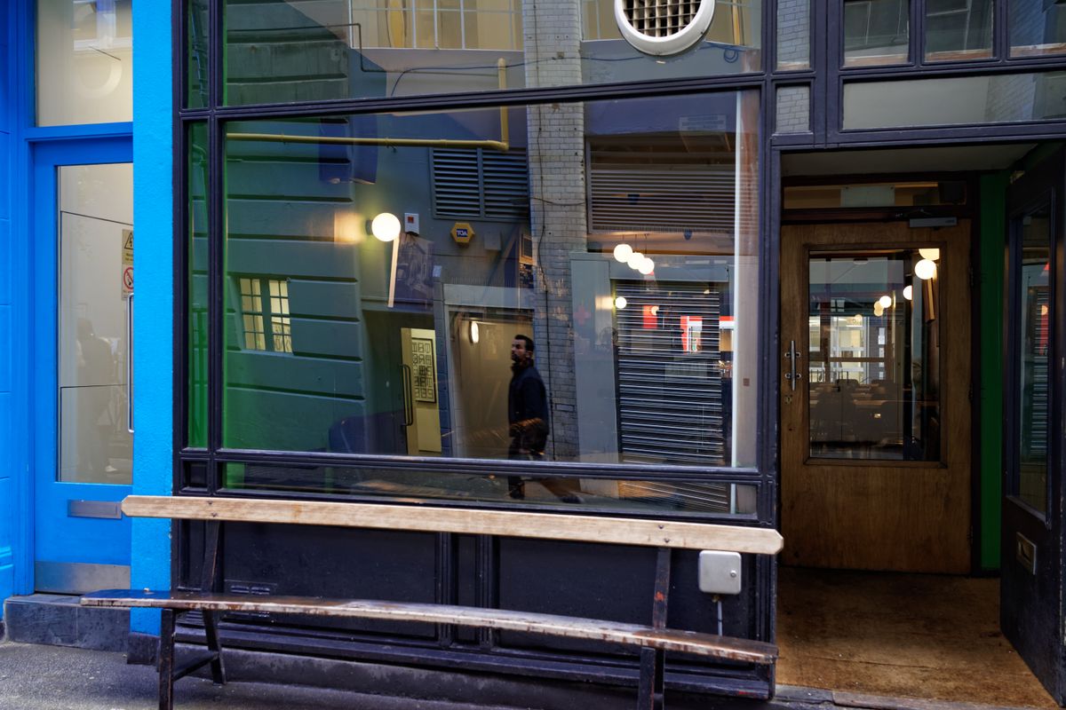 A man is caught in the reflection of a restaurant window on Carnaby Street, London.